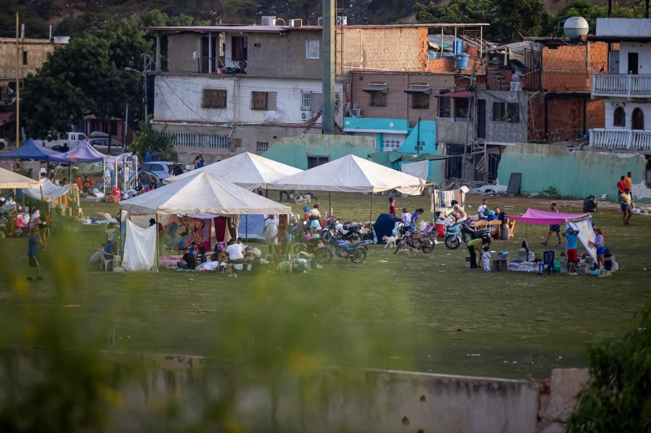 Campamento improvisado en un terreno con carpas blancas y familias afectadas por el terremoto